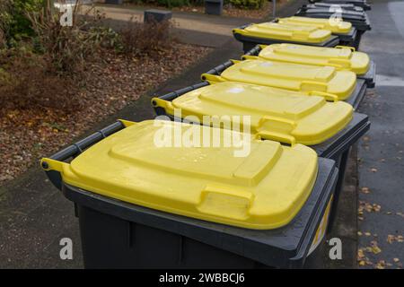 Coperchi gialli di contenitori per la raccolta degli scarti in plastica posti sul lato della strada. Foto Stock