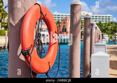 Lifebuoy arancione brillante sul molo con sfondo Marina Foto Stock