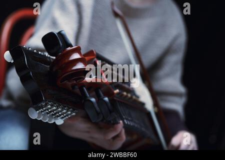 Le dita di un giocatore di Nyckelharpa ballano sulle chiavi, dando vita a melodie antiche ad ogni colpo di fiocco Foto Stock