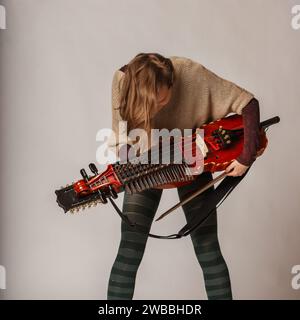 La musicista controlla attentamente il suo nyckelharpa, uno strumento tradizionale svedese raro, per garantire che ogni dettaglio sia perfetto Foto Stock