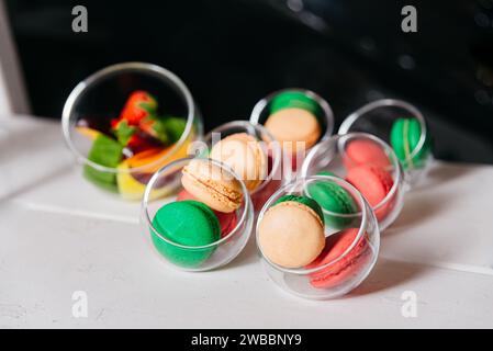 Macaron colorati assortiti presentati in tazze trasparenti, disposti su una superficie bianca per un dolcetto durante un evento. Foto Stock