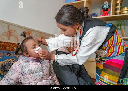 (240109) -- LHASA, 9 gennaio 2024 (Xinhua) -- Tenzin Drolma si prende cura di un bambino in una casa di riposo a Xigaze, nella regione autonoma Xizang della Cina sud-occidentale, 8 gennaio 2024. La gente del posto a Xigaze festeggia il Capodanno degli agricoltori il primo giorno del dodicesimo mese del calendario tibetano, che cade il 12 gennaio di quest'anno. Pasang, 44 anni, si sta preparando per le celebrazioni in una casa di benessere. Quest'anno è stato testimone del diciottesimo capodanno che Pasang ha celebrato qui. Insieme a Tenzin Drolma, che è venuto ad aiutare nel 2017, Pasang si assume la responsabilità di una madre per 13 figli Foto Stock