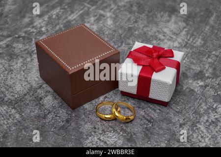 Custodia marrone, piccola confezione regalo e due anelli d'oro Foto Stock