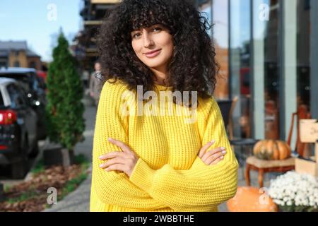 Giovane donna con elegante maglione giallo all'aperto Foto Stock