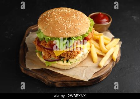 Delizioso hamburger con polpettine di pollo croccanti, patatine fritte e salsa sul tavolo nero Foto Stock