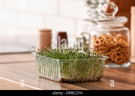 Contenitore in plastica con micro verde fresco sul tavolo in cucina Foto Stock