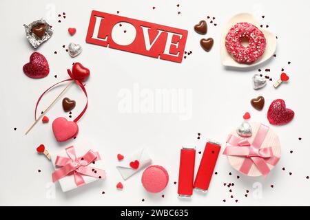 Cornice composta da diversi dolci gustosi, confezioni regalo e Love su sfondo bianco. Festa di San Valentino Foto Stock