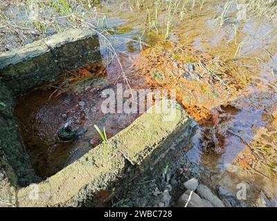 le perdite d'acqua dal terreno sono diventate torbide quando mescolate con il drenaggio. Foto Stock