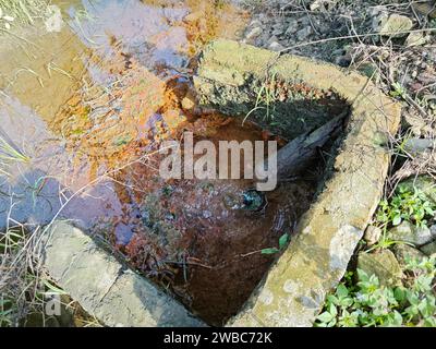 le perdite d'acqua dal terreno sono diventate torbide quando mescolate con il drenaggio. Foto Stock