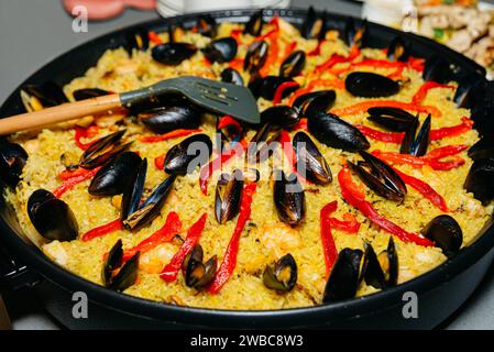 Una tradizionale paella di pesce con succulente cozze, peperoni rossi e un mix di spezie in una paella grande, pronta per essere servita. Foto Stock