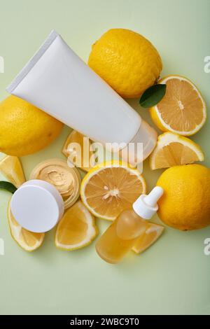 Mock-up di prodotti cosmetici naturali per la cura della pelle, tubo di plastica bianco, flacone contagocce e vaso panna senza etichetta con limoni freschi su sfondo pastello. S Foto Stock