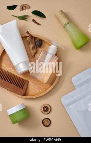 Scena per pubblicizzare prodotti cosmetici con un concetto minimale. Bottiglie mockup senza etichetta decorate con piatto di legno, pettine e maschera su sfondo beige Foto Stock