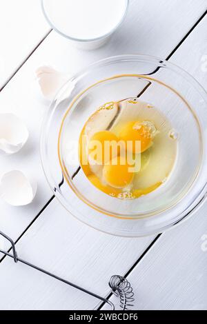 Tuorli d'uovo in un recipiente di vetro su sfondo di legno bianco Foto Stock