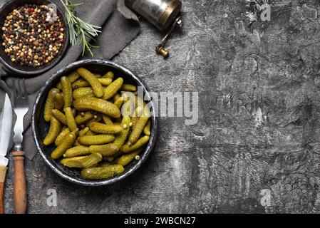 Sottaceti o cetriolini verdi in un recipiente su sfondo grigio chiaro. Deliziosa insalata invernale Foto Stock