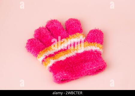 Guanti in maglia di lana caldi isolati su sfondo rosa. Guanti invernali per bambini caldi su un solo lato Foto Stock