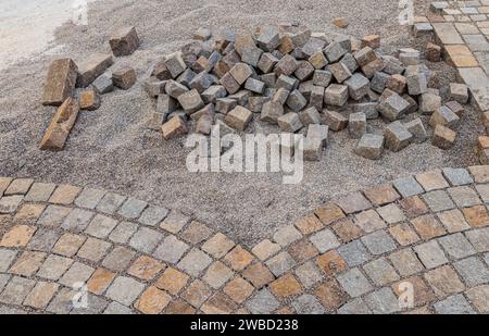 Ripavimentazione del fondo stradale, posa manuale di cubi di porfido sulla strada. Pavimentazione realizzata con cubi di Porfido rosso Trentino, Trentino alto Adige, Italia Foto Stock