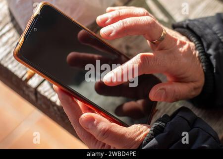 La mano di una donna che tocca lo schermo nero di un telefono cellulare Foto Stock