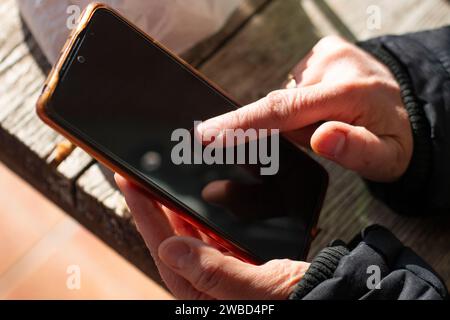 La mano di una donna che tocca lo schermo nero di un telefono cellulare Foto Stock