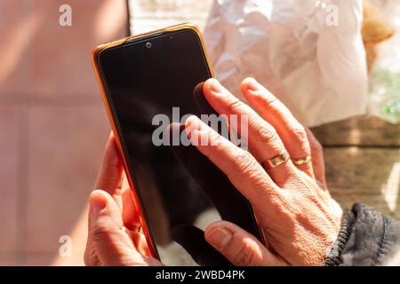 La mano di una donna che tocca lo schermo nero di un telefono cellulare Foto Stock