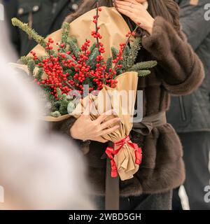 Mani di donna che tengono un bouquet di ilex rosso verticillata, bacca d'inverno per la decorazione natalizia Foto Stock