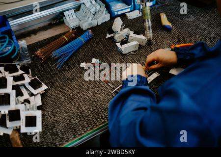 Elettricista edile al lavoro che ispeziona il collegamento dei cavi della linea elettrica ad alta tensione nella scatola fusibili di distribuzione industriale. Foto Stock