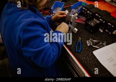 Primo piano delle mani di un giovane ingegnere informatico che ripara parti del pc rotte alla scrivania dell'ufficio domestico. Foto Stock