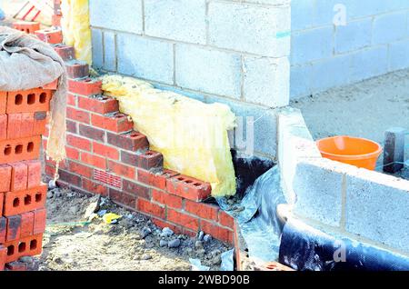 Isolare le pareti delle case di nuova costruzione posizionando lana di roccia all'interno delle cavità delle pareti come parte delle misure di risparmio energetico. Casa isolata con lana minerale Foto Stock