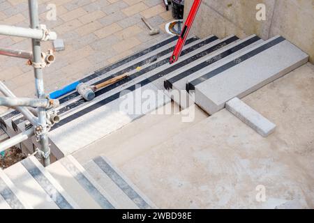 Passi concreti in costruzione come un team di costruttori installare blocchi di cemento pesanti Foto Stock