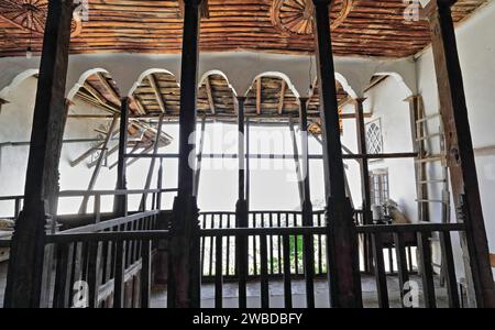 222+ vista dall'interno all'esterno, balcone centrale a sette archi con ringhiera in legno di una casa in stile ottomano nella parte superiore della città vecchia. Gjirokaster-Albania. Foto Stock