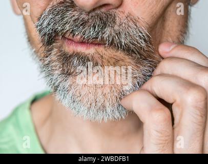 Uomo di mezza età che gratta con cura il suo viso incandescente in primo piano Foto Stock