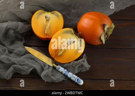 Cachi arancioni brillanti tagliati su fondo di legno Foto Stock