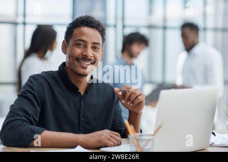 Un uomo d'affari allegro che lavora alla scrivania, sicuro di sé e impegnato. Foto Stock