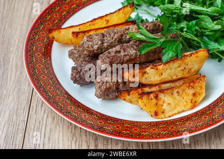 Kebab di Lula su un piatto bianco con bordo rosso con patate al forno e verdure. Kebab Lula di agnello, kebab di manzo lula, kebab di pollo da vicino. Foto Stock