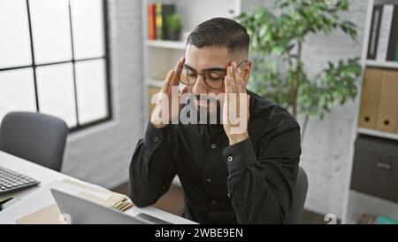 Un uomo d'affari stressato in ufficio che sfrega le tempie Foto Stock