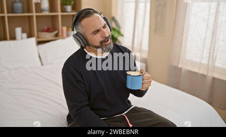Un uomo ispanico maturo si diverte con caffè e musica con le cuffie in un ambiente accogliente. Foto Stock