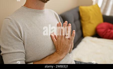 Un uomo ispanico di mezza età con la barba pratica yoga in un accogliente soggiorno, trasudando tranquillità e concentrazione. Foto Stock