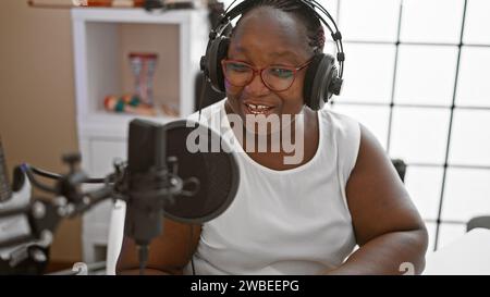 Donna reporter afroamericana che indossa cuffie che presentano notizie allo studio radio Foto Stock