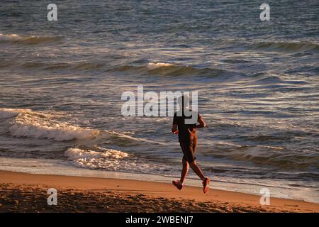 un uomo che corre sulla spiaggia, che corre in mare, il mare sullo sfondo Foto Stock