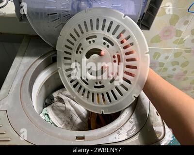 Lavare gli indumenti e far girare gli indumenti nel serbatoio per la pulizia a secco della vecchia lavatrice. Foto Stock