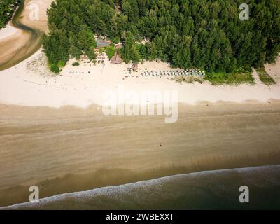 Vista aerea dall'alto degli ombrelloni su una grande e tranquilla spiaggia tropicale con bassa marea Foto Stock
