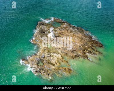 Vista aerea di un piccolo faro situato su una roccia al largo da una spiaggia tropicale Foto Stock