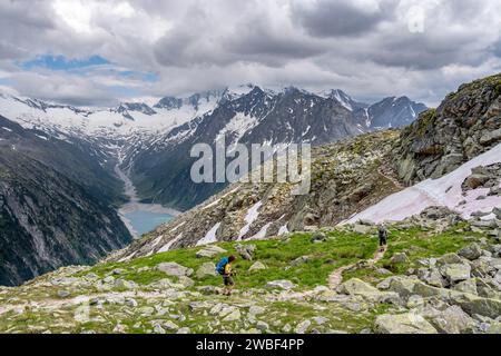 Two mountaineers on hiking trail, view of Schlegeisspeicher, glaciated rocky mountain peaks Hoher Weisszint and Hochfeiler with glacier Stock Photo