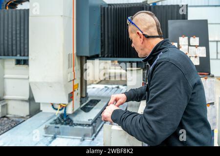 Vista posteriore di un ingegnere che lavora in una fresatrice cnc Foto Stock