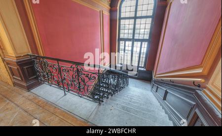 Area d'ingresso con scala curva, pareti rosse ed elementi in legno, Villa Woodstock, Lost Place, Wuppertal, Renania settentrionale-Vestfalia, Germania Foto Stock