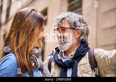 Allegra coppia caucasica attraente che fa un selfie romantico all'aperto sorridendo l'uno all'altro. Foto Stock