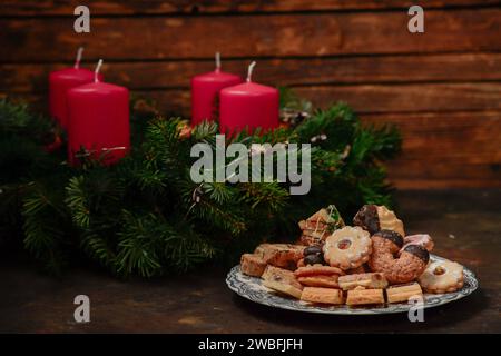 Corona di Natale con candele rosse in rami di pino con biscotti nella stagione dell'Avvento Foto Stock