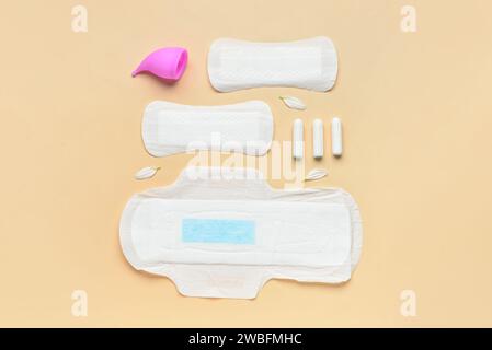 Composizione con tamponi mestruali, coppa e tamponi su sfondo beige Foto Stock