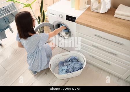 Giovane donna incinta che fa il bucato a casa Foto Stock