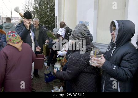 Non esclusiva: VINNYTSIA, UCRAINA - 6 GENNAIO 2024 - Un sacerdote benedice la congregazione con acqua Santa fuori dalla Cattedrale della Trasfigurazione della nostra S. Foto Stock