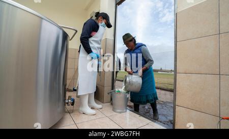 Chambitola, Cayambe / Ecuador - 1 novembre 2023: Donna indigena che scarica latte appena munto in un secchio, all'ingresso del centro di raccolta Foto Stock